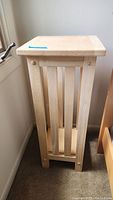 Side view of one wooden two-tier plant stand showing vertical slats and natural wood finish.
