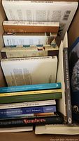 Top view of a box of signed hardcover books showing various titles including "Natural History Exchange", "Dear Mother", and environmental and local history books.