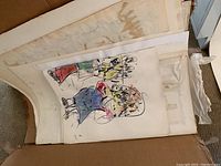View of several unframed abstract art pieces stacked, including a colorful loosely sketched figure.