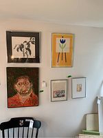 Five wall art pieces hanging on wall including self portrait and botanical prints.
