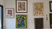 Photo showing five pieces of art hung on wall including a variety of styles and mediums with size and damage noted