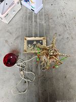 Photo showing the Asian style lamp, ruby glass tea cup, and framed dried flower art together on the floor.