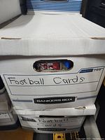 Front view of a white Banker's Box labeled 'Football Cards' containing the football card collection.