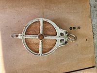 Top view of the farm style pulley, showing the round wheel, spoke design, and loop for hanging.