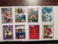 Top front view of eight football cards in clear protective sleeves, showing various player action shots and card brands