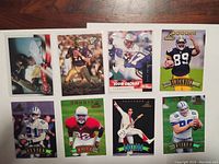 Front view of all 8 football cards arranged in two rows of four on a wooden surface showing player images and design details.