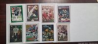 Front view of 8 football cards laid out flat on wood surface revealing players in uniforms and front design