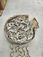 Box filled with numerous old brass plate window locks showing their general quantity and condition, some still tarnished and worn.