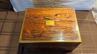 Top view of closed wooden jewelry box showcasing wood grain and brass trim.