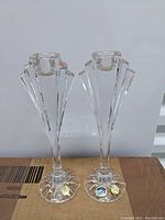 Two taller Bohemian crystal candle holders with vertical cuts and starburst bases, showing original labels