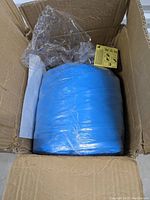 Box containing the folded blue inflatable pool wrapped in clear plastic, showing compact packaging.