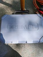 Closed gray plastic carrying case with embossed Dremel logo on the lid.