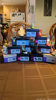 General view of 10 decorative shoe figurines on boxes stacked in pyramid formation on table.