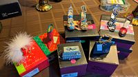 Overview of 8 shoe decorative figurines in original boxes arranged on table.
