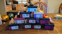 Stacked boxes of Boston Collection doll shoes with various styles visible on top including black Mary Jane shoe and yellow loafer shoe