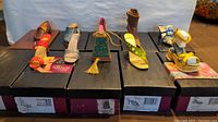 Front view of 10 miniature collectible shoes arranged in original boxes showing variety in style and colors.