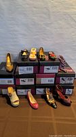 Lot of 10 women's shoes displayed on and beside stacked original shoeboxes in like new condition.