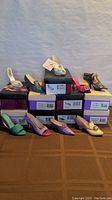 Lot of 9 women's collectible shoes in original boxes displayed on table, varying colors and types visible