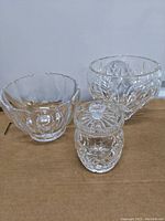 Two Lenox clear glass bowls and one Waterford crystal jelly jar with lid on cardboard surface.