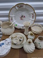 Photo showing all Lenox gold label porcelain items including large plate, ashtray, water pitcher, basket bowl, napkin rings and plates, plus Beleek pieces and cat figurine.