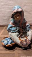 Front view of the Lladro porcelain figurine showing the fish vendor seated with basket of fish
