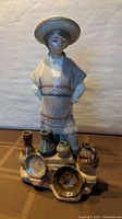 Full view of the porcelain figurine showing boy and pottery items