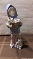 Front view of Lladro figurine showing child holding basket with three kittens and two cats at feet.