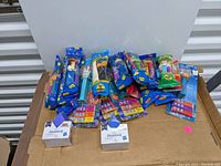 Photo showing a variety of PEZ dispensers in sealed plastic packaging with multiple character themes visible.