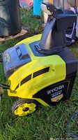 Side view of Ryobi 40V snow blower showing yellow and black body and rear wheel