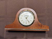 Front view of the Seth Thomas mini mantle clock showing wood casing, brass bezel, white dial face, and clock hands.