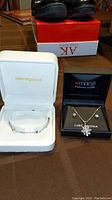 Photo showing a Sterling silver bracelet in Bloomingdale's white jewelry box and a sterling silver cubic zirconia necklace with matching stud earrings in Macy's black jewelry box.