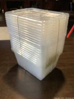 Stacked set of 10 small translucent Kris storage containers with lids, secured with rubber bands.