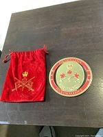 Photo of the 6-inch round plaque with Canadian Army insignia and the red velvet bag embroidered with crown and crossed swords.