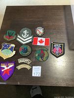 Group of 12 embroidered arm patches arranged on a wooden surface