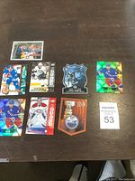 Top-down photo showing 8 hockey cards arranged on a wooden surface, including Evgeni Malkin, Carey Price, and Rick Nash cards.
