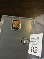 Minecraft game cartridge inside partially transparent plastic case on a dark wood surface