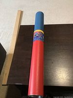 Cylindrical protective tube with Superman-themed design for storing the uncut stamp sheet