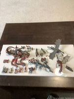 Top view of all figurines on white background showing large red and black multi-headed dragon and smaller warrior figurines