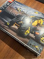Front of LEGO Technic box showing loader in a rugged construction scene with city skyline in the background.