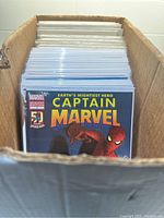 Box of comic books with Captain Marvel #1 variant edition visible at the front.