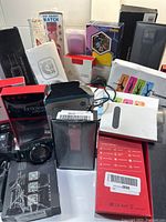 Overview photo showing multiple digital watches, boxes, and accessories in the lot with some packaging visible such as kid smart watch and sport bracelet charger.