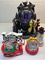 Front view of all 5 Disney snow globes, showing large Maleficent villain globe in center with smaller globes of Mickey Mouse, 101 Dalmatians, snowman, and NOEL design.