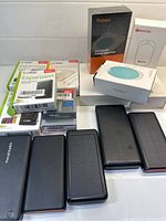 Photo showing KESU external hard drives in original packaging along with multiple black external devices and boxed hand warmers.
