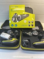 Three Roziapro electric grooming kits in their cases with multiple attachments visible, box showing 5-in-1 grooming kit branding