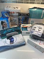 Group view of various health care and therapy products including blood pressure monitor, wrist brace, gel pack, and other boxed items.