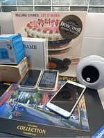 View of lot showing puzzles, iPods, iPhone, clock, and small electronic device