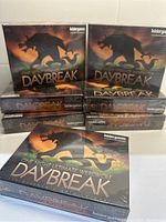 Photo showing multiple sealed boxes of One Night Ultimate Werewolf Daybreak stacked, highlighting the front cover art with werewolf silhouette.