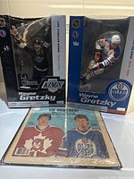 Two Wayne Gretzky hockey figures in original boxes and vintage newspaper in front of the figures.