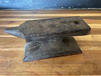 Side view of antique metal anvil showing its tapering horn and flat top surface.