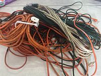 Overview of tangled extension cords in various colors including orange, black, white, and green.
